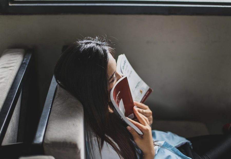 深夜书桌前，一位读者开着台灯用手机看小说txt下载 App 的夜间模式，屏幕米黄背景与暖色灯光叠在一起，桌角放着一杯凉掉的茶